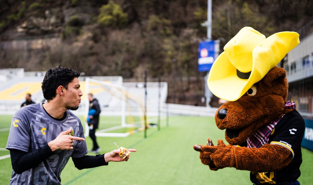 Dani Rovira posing for a picture with Pittsburgh Riverhounds Mascot AMO after a practice at Highmark Stadium.