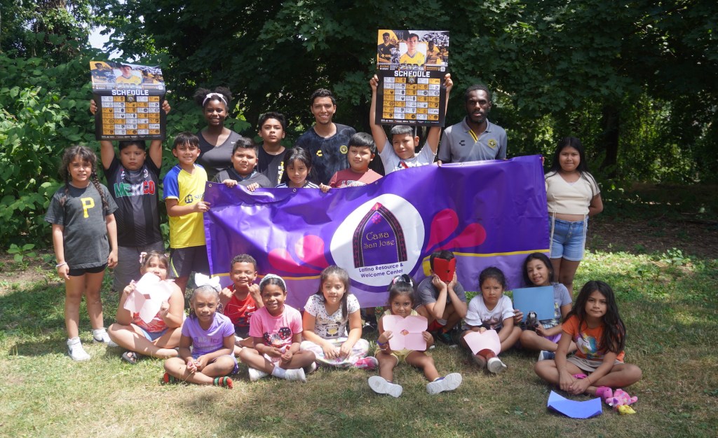 Hounds players Dani Rovira and Junior Etou pose for a photo with the children at the Casa San José summer camp in Beechview.