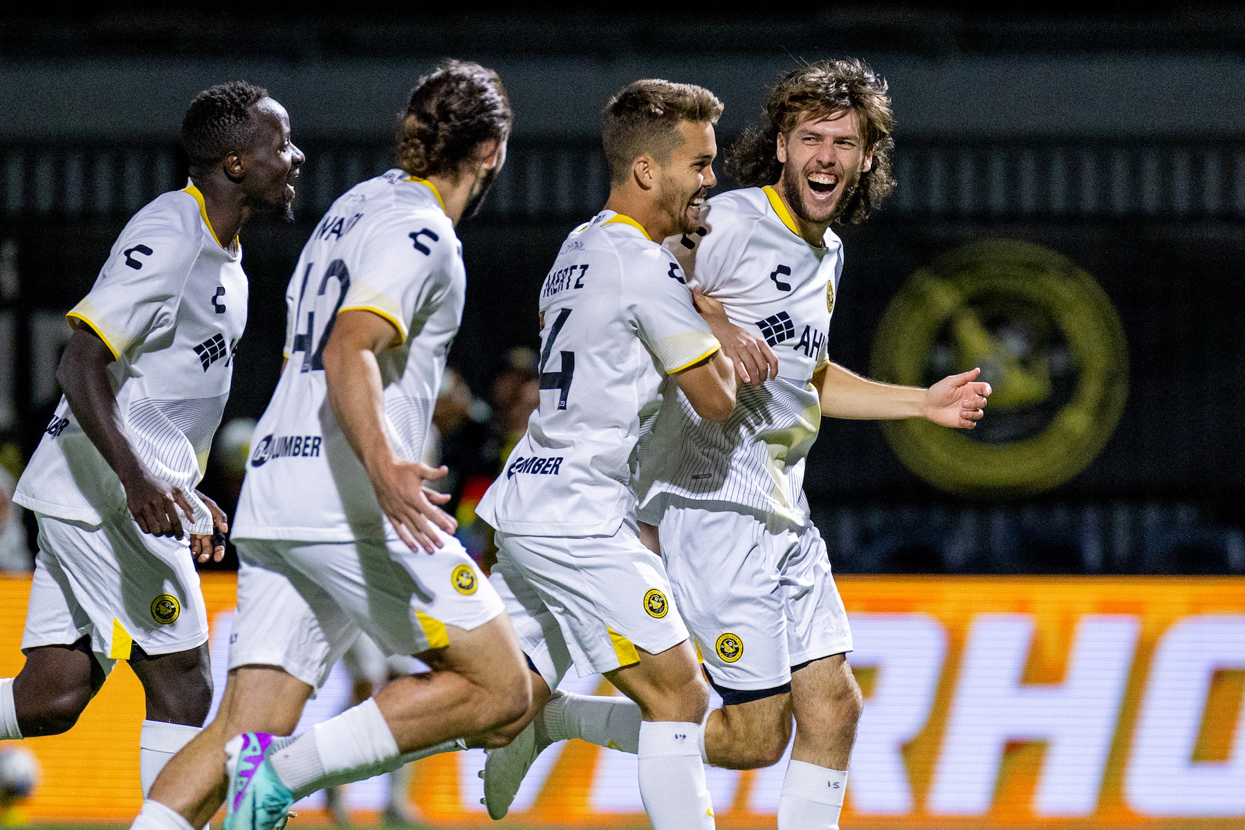 Hounds players follow Bradley Sample as he celebrates his first professional goal in the Hounds' 2-0 win over Rhode Island FC on Sept. 7, 2024 at Highmark Stadium. (Photo: Chris Cowger/Riverhounds SC)