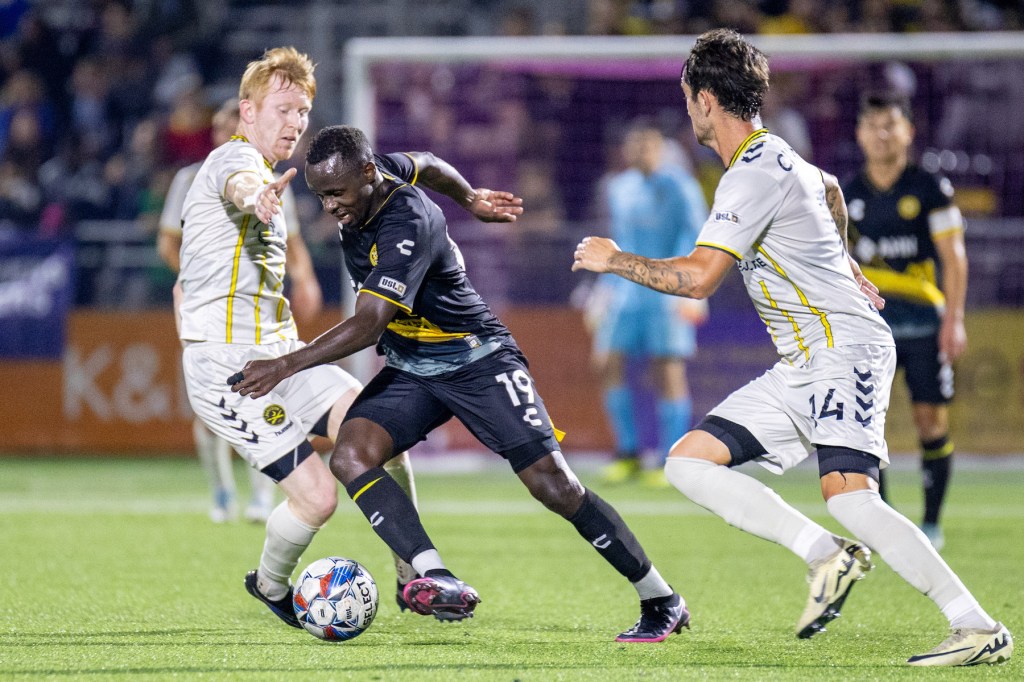 Hounds forward Edward Kizza dribbles between a pair of Charleston Battery defenders in the team's 2-0 win on Oct. 12, 2024 at Highmark Stadium. (Photo: Chris Cowger/Riverhounds SC)