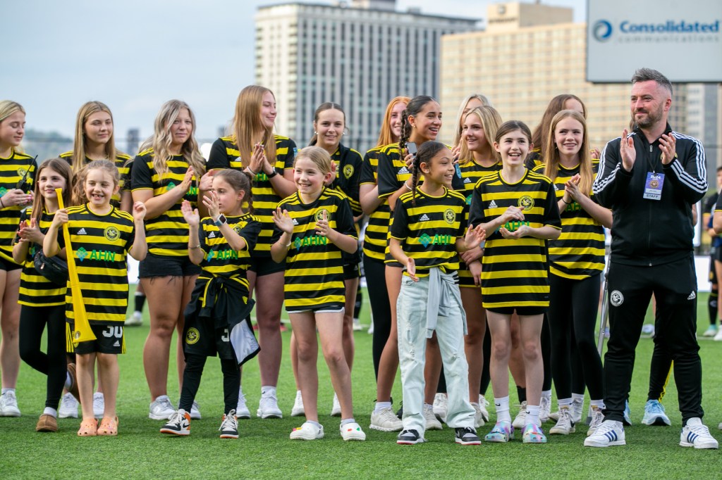 Riveters head coach Scott Gibson and girls players from the Riverhounds Development Academy cheer on the field after the announcement of Pittsburgh's W League team — later to be named the Riveters — before a Riverhounds match on April 27, 2024, at Highmark Stadium.